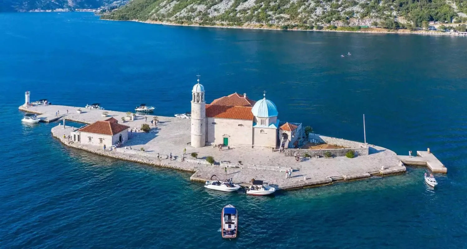 Aerial view of Our Lady of the Rocks in Montenegro, a historic artificial island with a church in the Bay of Kotor.