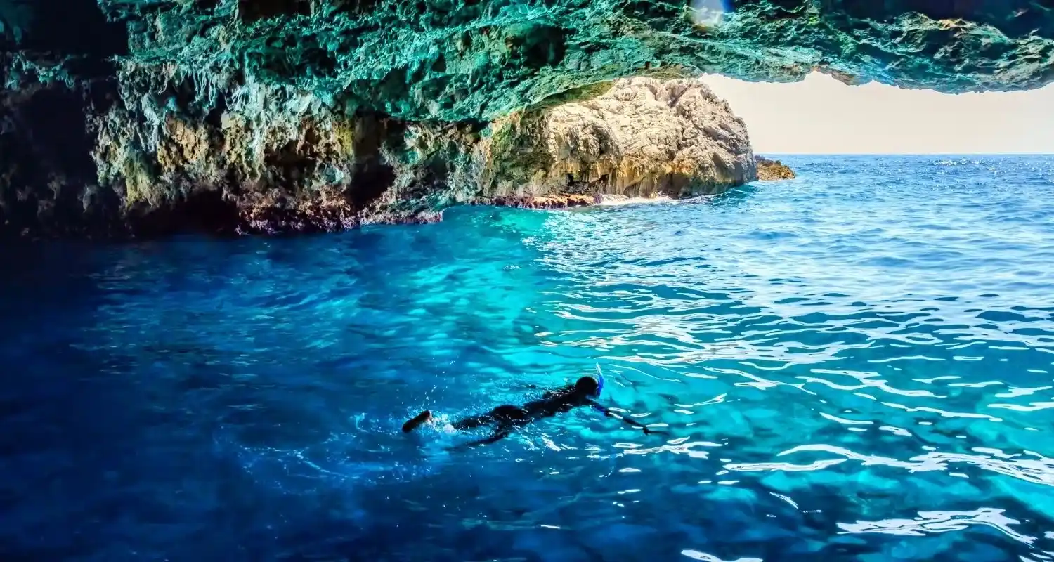 Snorkeler swimming through the luminous turquoise water of the Blue Cave on the Luštica Peninsula