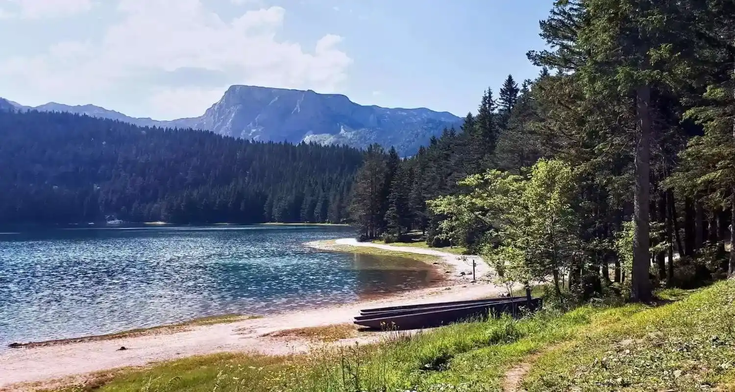 Mirni dio obale Crnog jezera sa čamcem i pogledom na Durmitor 