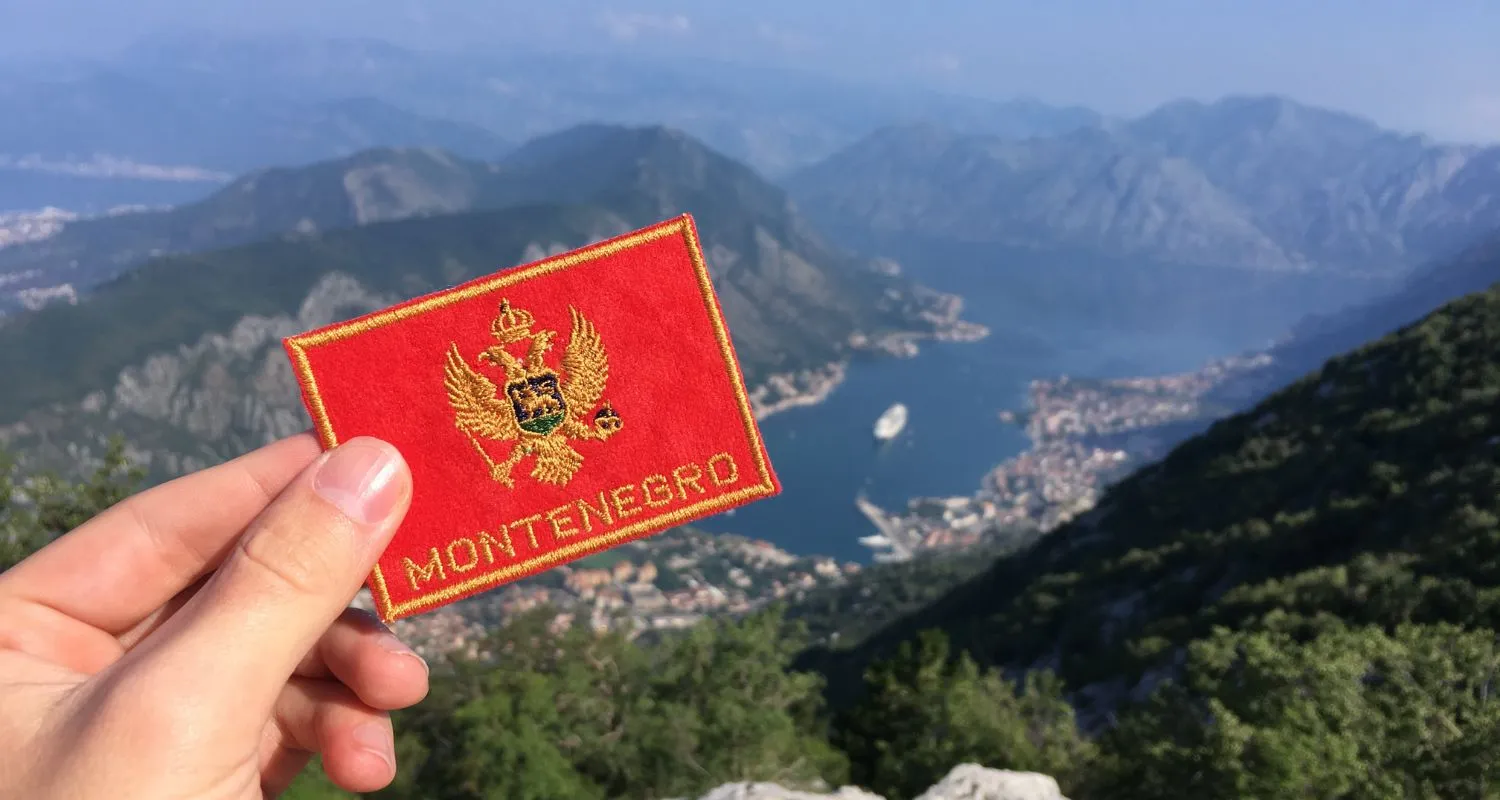 Montenegro bedž u ruci sa pogledom na Boku Kotorsku