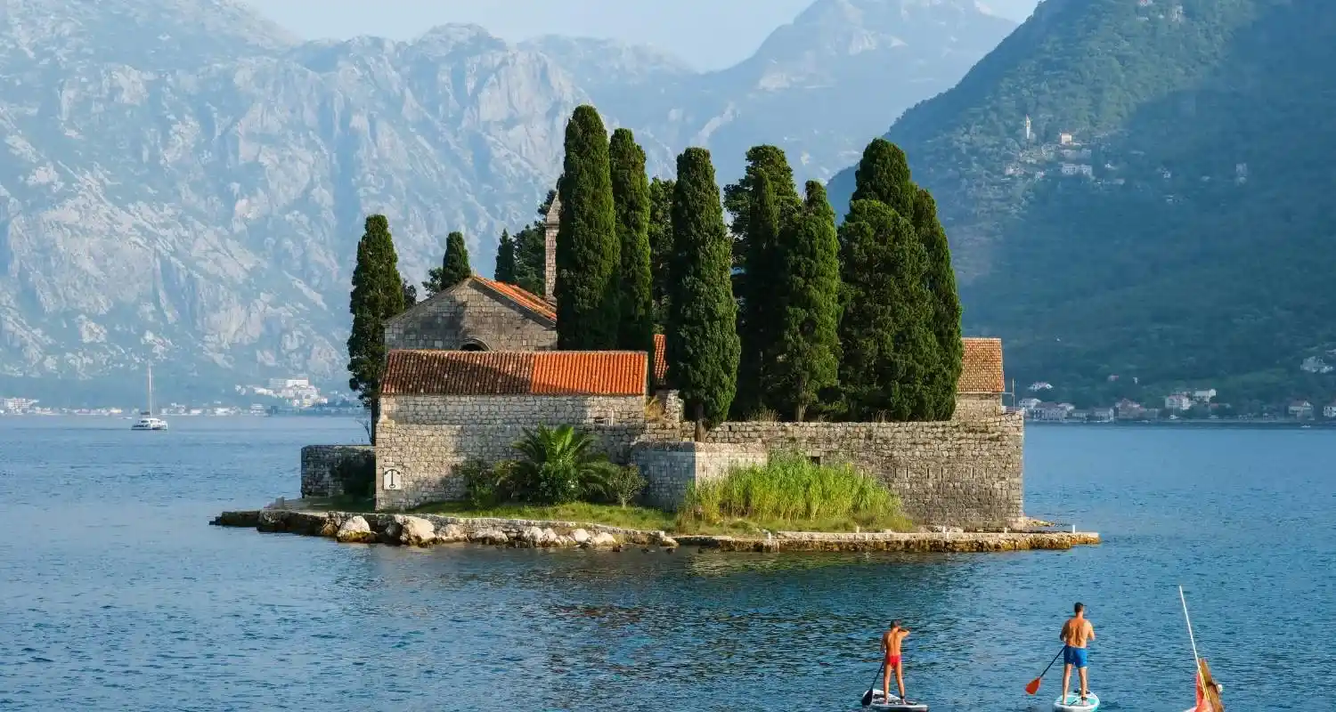 Saint George Island near Perast with a stone monastery, cypress trees, and the Bay of Kotor in the background
