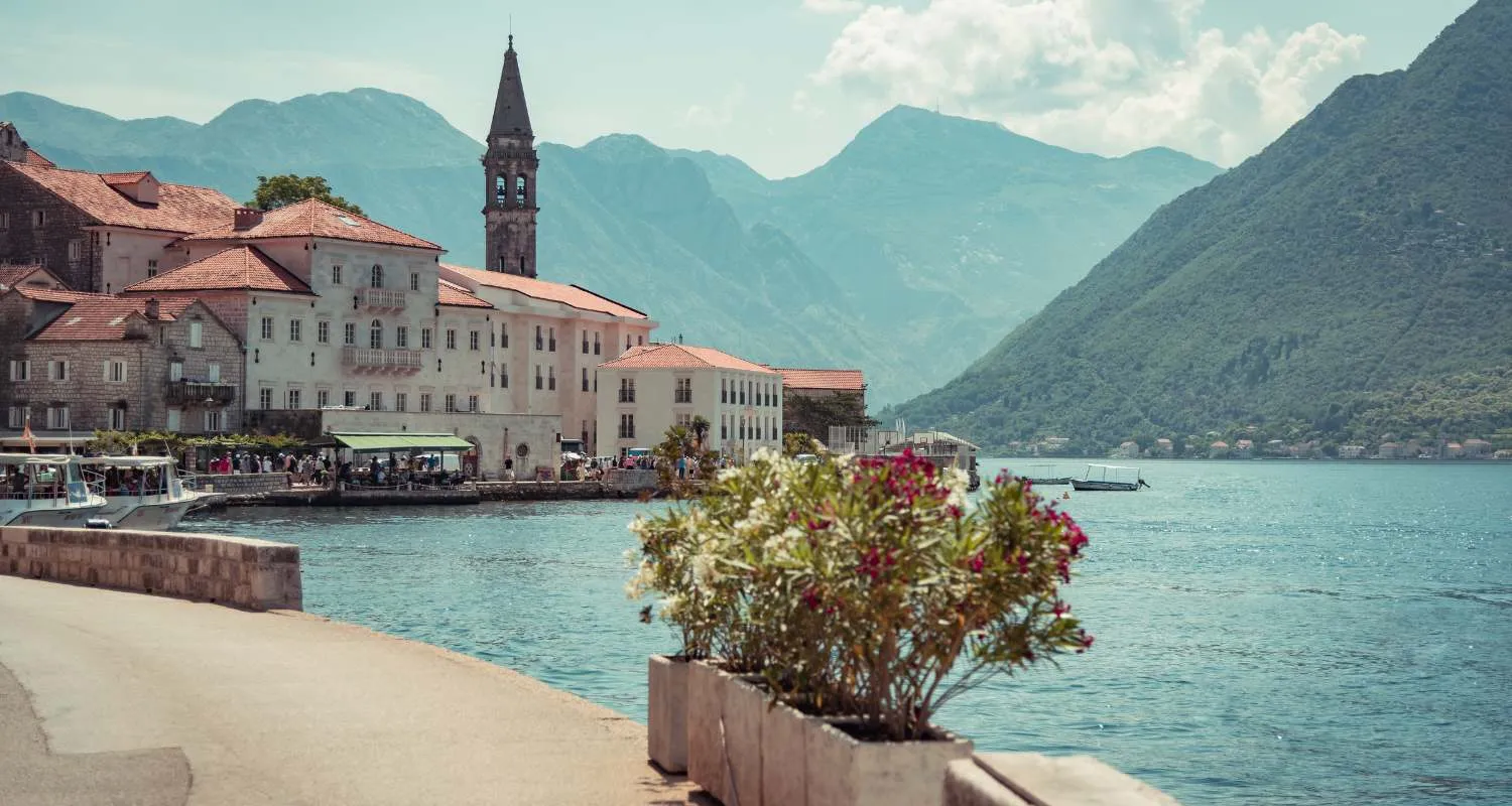 Waterfront promenade in Perast with a view of the church bell tower, sea, and mountains of the Bay of Kotor