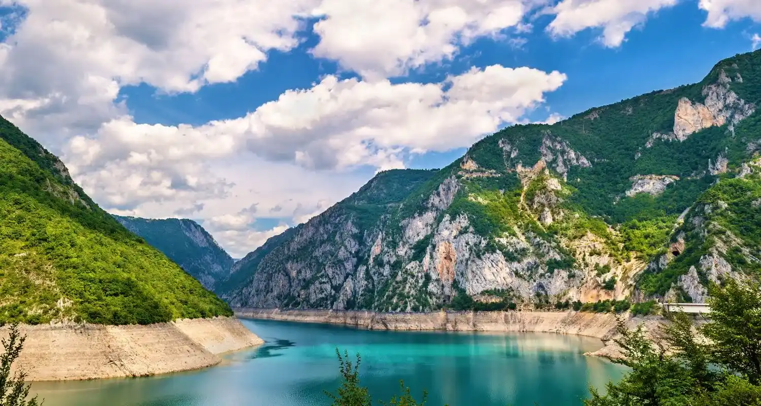 Piva Lake with turquoise water surrounded by steep green mountains and rocky shores