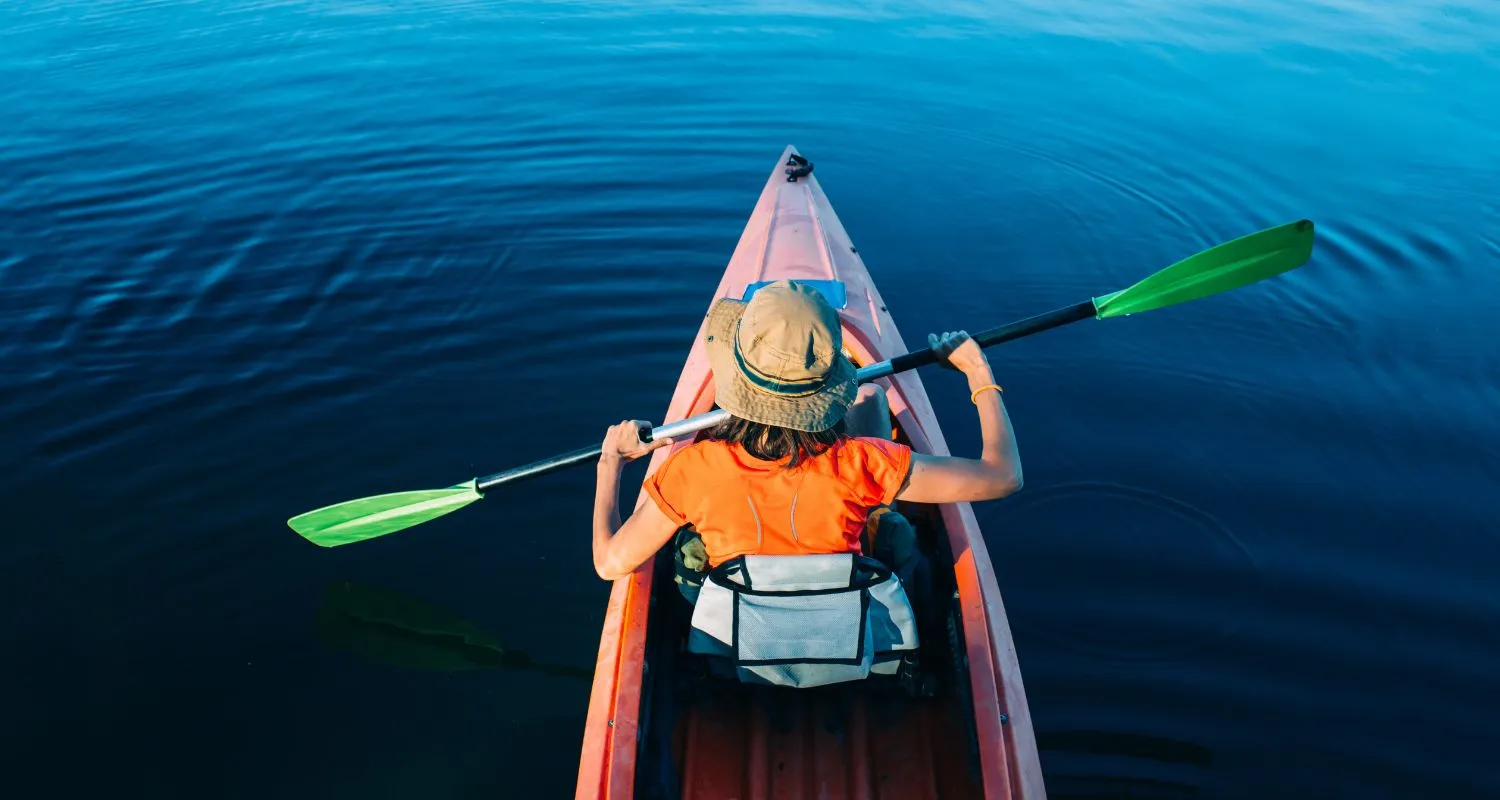 Person paddling a kayak across the calm blue water of Piva Lake