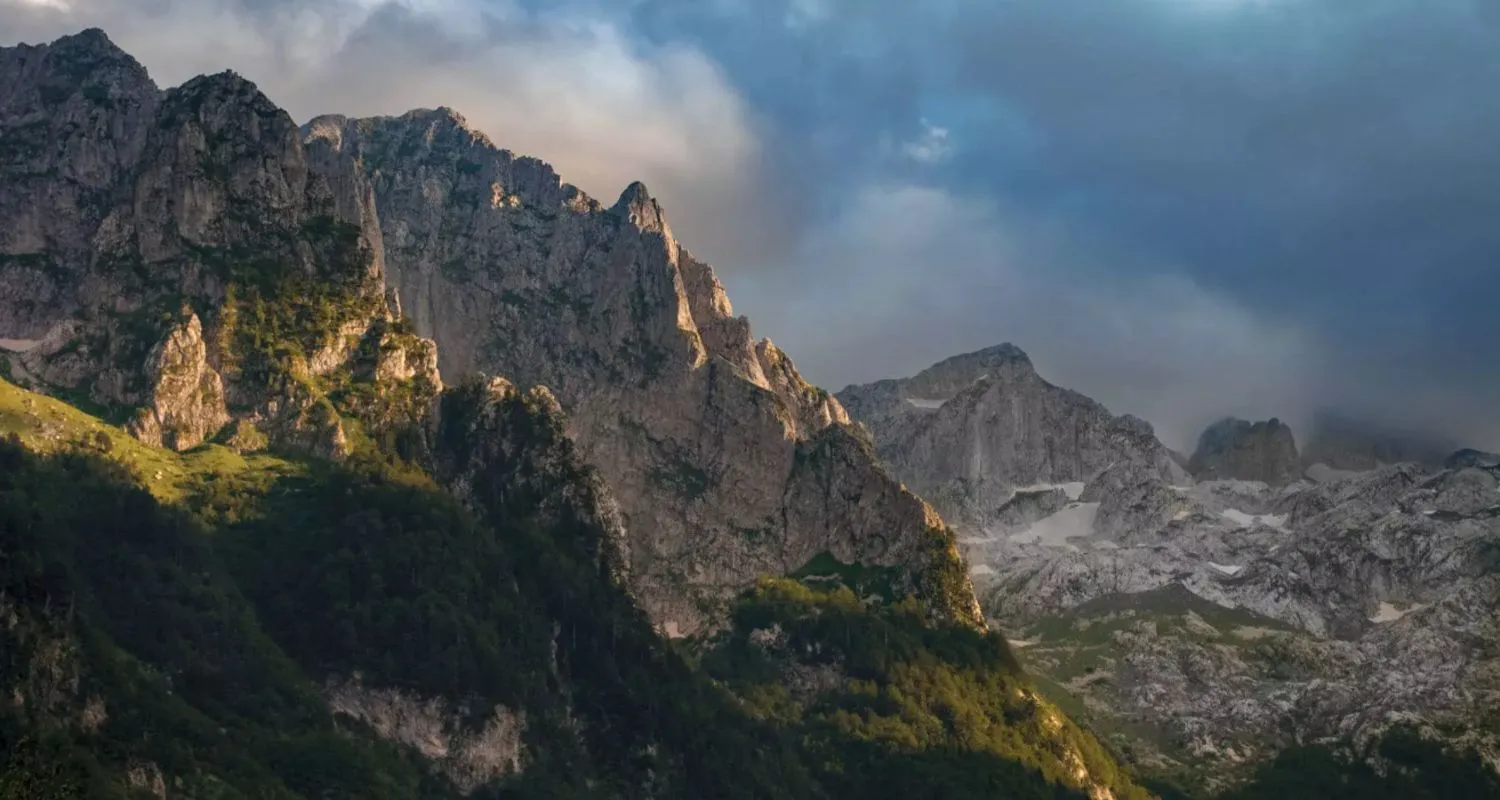 Sunlight breaking across the cliffs of Prokletije National Park beneath dark clouds